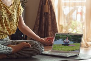 Sporty young woman taking yoga lessons online and practice at home while being quarantine. Concept of healthy lifestyle, wellness, being safe while coronavirus pandemic, looking for new hobby.